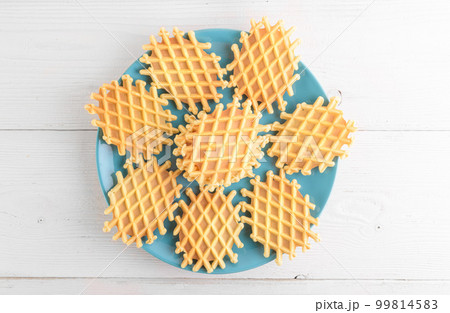 Ferratelle or pizzelle a traditional dessert or cookies from Abruzzo on a blue plate on a white wooden background 99814583