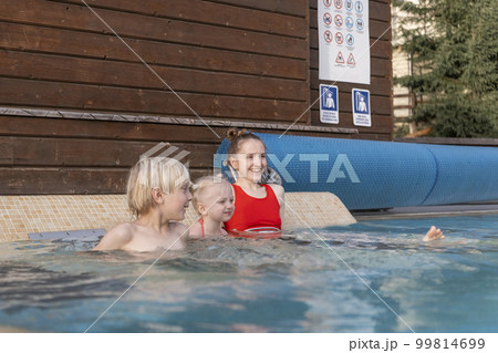 Young mother or sister and children swim in pool. Woman and two kids at outdoor swimming pool Young mother or sister and children swim in pool. Woman and two kids at outdoor swimming pool 99814699