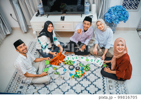 group of smiling Asian Muslims sitting preparing Eid decorations 99816705