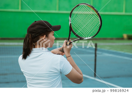 back of the shoulder of a female tennis athlete hitting 99816924