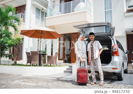 Muslim couple standing behind the trunk of car holding suitcases Muslim couple standing behind the trunk of car holding suitcases 99817250