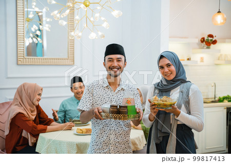 husband and wife serving food for family for break fasting 99817413