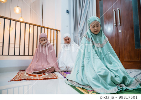 Asian Muslim woman in Muslim dress doing Tashahud sitting movement 99817501