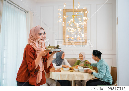 Beautiful veiled girl carrying a plate of rice cake 99817512
