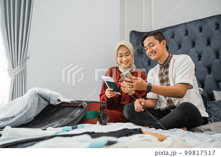 Asian Muslim couple use phones together to search for tickets 99817517