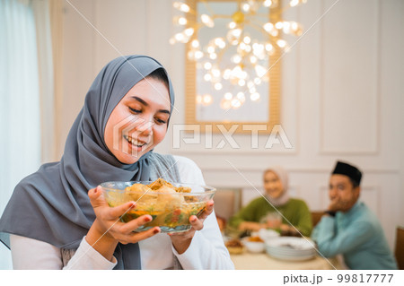 Beautiful veiled girl carrying a plate of food 99817777