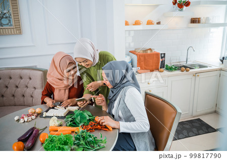 friend with hijab looking at the phone to make food 99817790