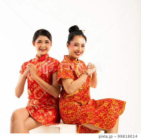 two woman in cheongsam sitting while greetings for lunar new year 99818014