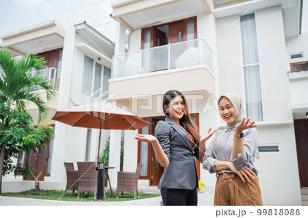 two female real estate agents with a hand gesture presenting two female real estate agents with a hand gesture presenting 99818088