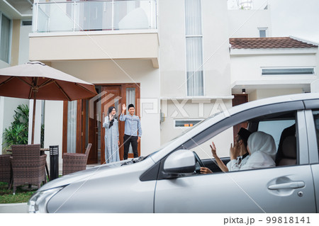 Asian Muslim husband and wife wave to guests arriving 99818141