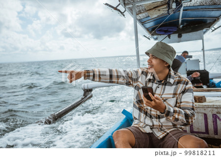 caped angler using cell phone with finger pointing on boat caped angler using cell phone with finger pointing on boat 99818211