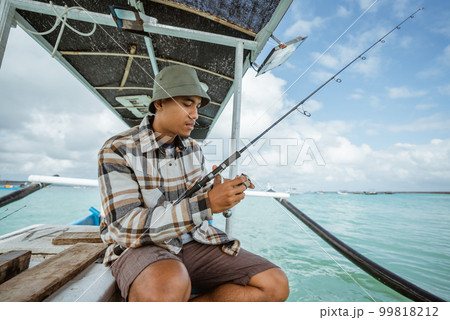angler holding a fishing rod and checking the reel 99818212