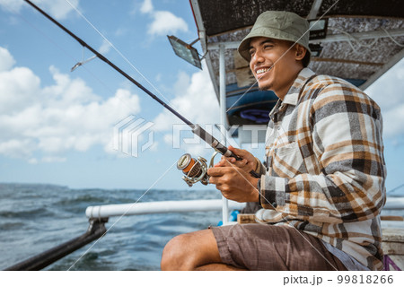 fishermen reel in fishing line while casting on fishing boat 99818266