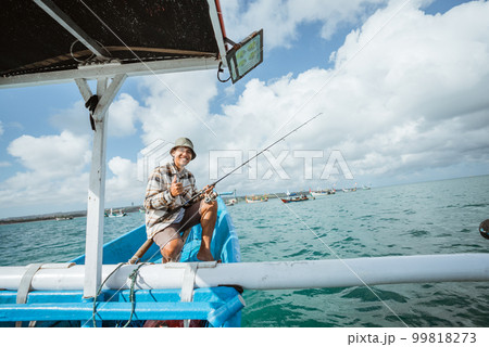 angler sitting at the boat with thumbs up 99818273