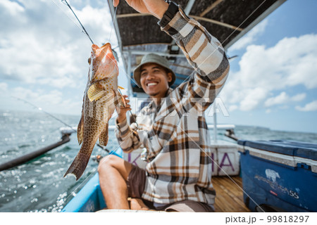 big grouper caught by an Asian angler with fishing rod 99818297