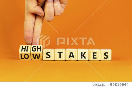 High or low stakes symbol. Concept words High stakes and Low stakes on wooden cubes. Businessman hand. Beautiful orange table orange background. Business high or low stakes concept. Copy space. 99819644