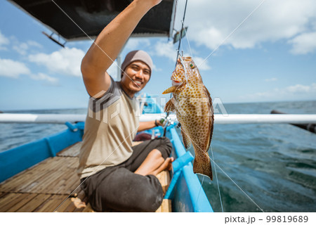 A grouper is hooked while fishing with a fishing rod 99819689