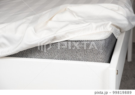 White satin sheet on an elastic band on the mattress. Bed linen on the bed 99819889