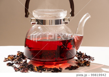 Red hibiscus tea from the petals of a Sudanese rose in a glass teapot Red hibiscus tea from the petals of a Sudanese rose in a glass teapot 99819942