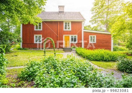 Historic red wooden house surrounded by trees and grass at Skansen Museum in Stockholm, Sweden Historic red wooden house surrounded by trees and grass at Skansen Museum in Stockholm, Sweden 99823081