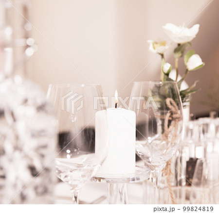 Festive decorated table in a restaurant, candle, wine glasses, vase, flowers on a white tablecloth. Restaurant, celebration, wedding Festive decorated table in a restaurant, candle, wine glasses, vase, flowers on a white tablecloth. Restaurant, celebration, wedding 99824819