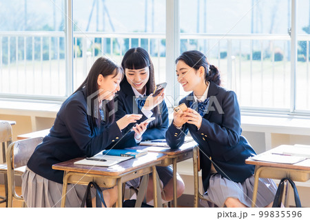 教室でクラスメイトとスマホを見ながら話す女子高生 教室でクラスメイトとスマホを見ながら話す女子高生 99835596