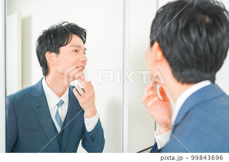 鏡の前で肌荒れを気にする若いサラリーマンの男性 99843696