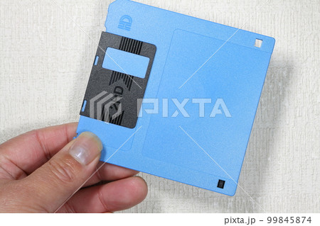 手に持ったフロッピーディスク 99845874