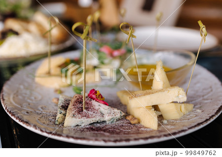 Four types of different cheeses sliced and served on a plate with honey sauce. Four types of different cheeses sliced and served on a plate with honey sauce. 99849762