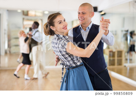 Man and woman performing ballroom dance in dancing room 99850809