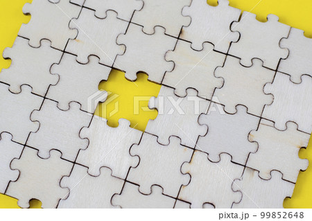 Assembled puzzle background. One missing wooden puzzle on a yellow background. The concept of completing a case 99852648