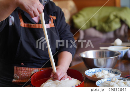 つきたてのお餅に食材を絡める女性 99852845