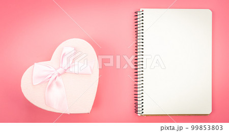 Blank notebook and heart shaped gift box on pink background, top view. Blank notebook and heart shaped gift box on pink background, top view. 99853803
