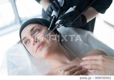 Young caucasian woman on microcurrent therapy procedure. Beautician's office. Young caucasian woman on microcurrent therapy procedure. Beautician's office. 99856002