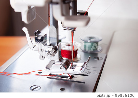 Modern sewing machine presser foot with red thread close up 99856106