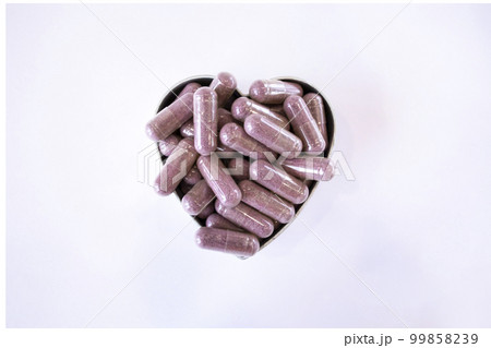 Pink capsules with supplements on a white background in the shape of a heart. Tablets and medications 99858239