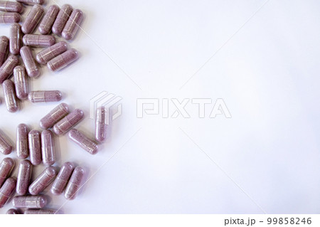 Pink capsules with additives on a white background. Tablets and medicines. Vitamins, minerals, plant extracts and other useful substances. Top view, copy space 99858246