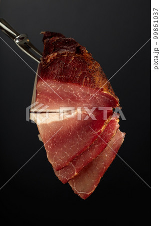 Dry-cured pork fillet on a fork. Dry-cured pork fillet on a fork. 99861037