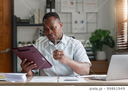 American African Businessman research and analysis with financial graph at office. Strategy, chart, finance report concept 99861949