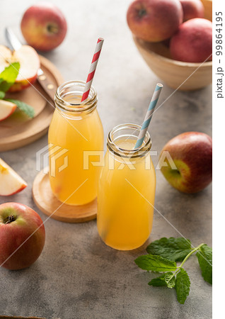 Apple juice glass bottles, with fresh red apples, wooden background. Apple juice glass bottles, with fresh red apples, wooden background. 99864195