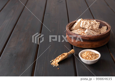 Pieces of tahini halva in a bowl on dark wooden background 99864635
