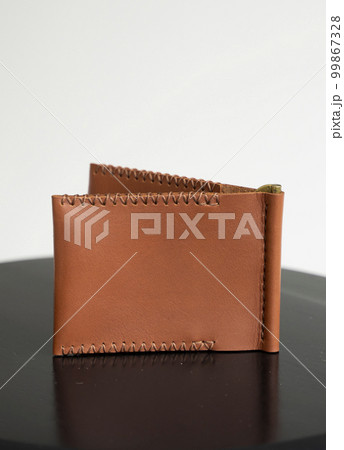 Orange men's money clip handmade leather wallet with a two pockets on a black table. Orange men's money clip handmade leather wallet with a two pockets on a black table. 99867328