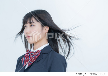 髪をなびかせる制服を着た女子高生の上半身 99873307