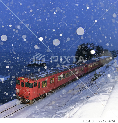 雪降る冬の氷見線（走り去る列車を後方から撮影） 99873698