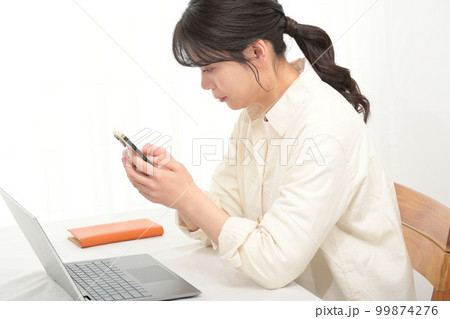 机でスマホを見る若い女性 99874276
