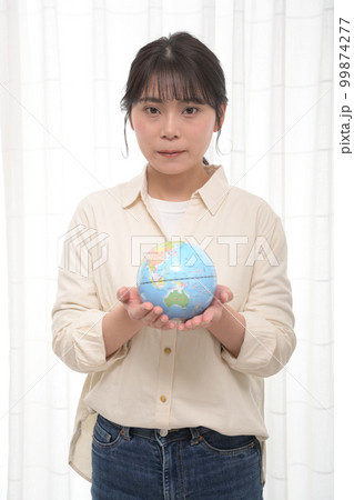 部屋で地球儀を持って立つ若い女性 部屋で地球儀を持って立つ若い女性 99874277