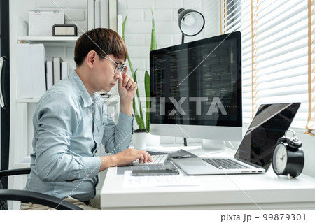 Male programmer is programming to develop program app and website of corporate while working to checking program code and debugging on multiple screen at modern software office Male programmer is programming to develop program app and website of corporate while working to checking program code and debugging on multiple screen at modern software office 99879301