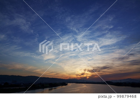 飛行機雲が現れた春の朝焼け空と反射する川・空主体・220502am 99879468