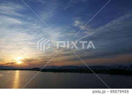 飛行機雲が現れた春の朝焼け空と反射する川・空主体・220502am 99879489