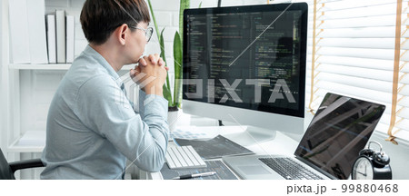 Male programmer is programing to developing program app and website of corporate while working to checking program code and debugging on multiple screen at modern software office 99880468
